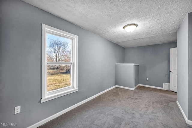 carpeted spare room with a textured ceiling and baseboards