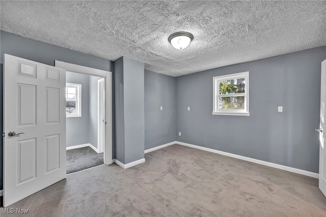 empty room featuring baseboards, carpet floors, and a textured ceiling