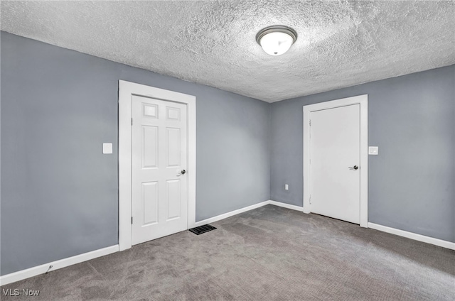 carpeted empty room with visible vents, baseboards, and a textured ceiling