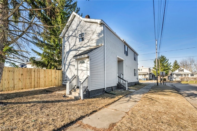 exterior space featuring entry steps, a chimney, and fence