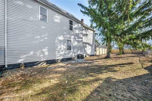 view of side of home with fence and a chimney