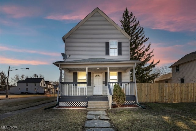 view of front of house featuring fence, covered porch, and a lawn