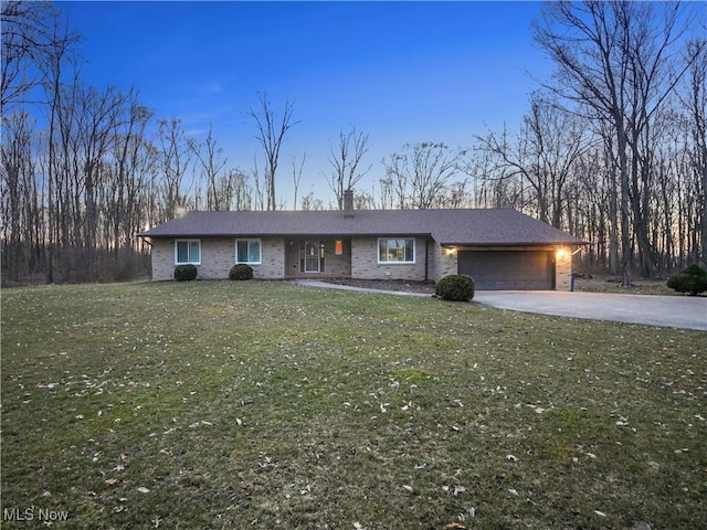 view of front facade with a front lawn, aphalt driveway, an attached garage, brick siding, and a chimney