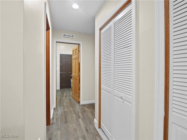 corridor featuring light wood finished floors and baseboards