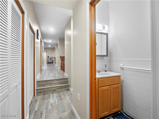 bathroom with wainscoting, tile walls, wood finished floors, and vanity