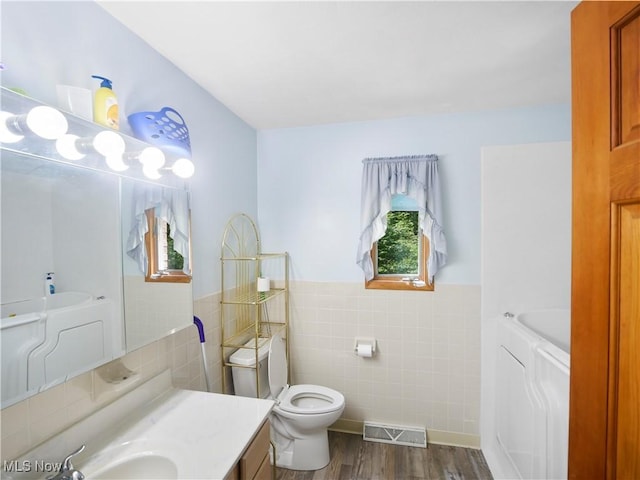 bathroom featuring visible vents, plenty of natural light, tile walls, and toilet