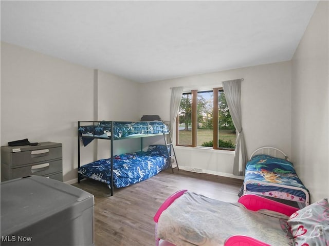 bedroom with visible vents, baseboards, and wood finished floors