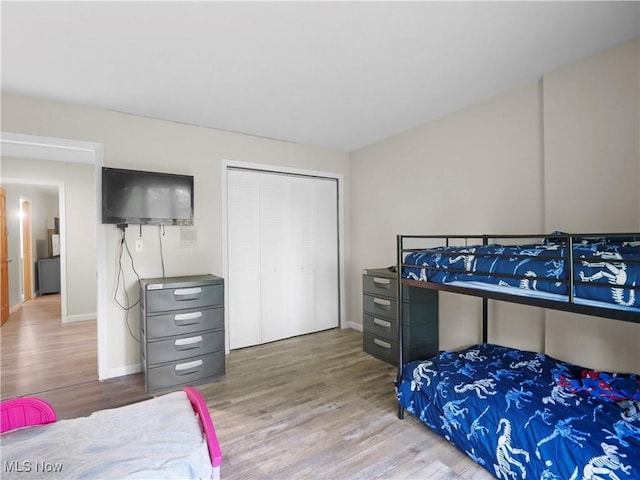 bedroom with a closet, baseboards, and wood finished floors