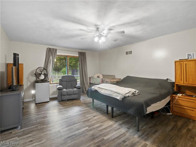 bedroom featuring visible vents, baseboards, wood finished floors, and a ceiling fan