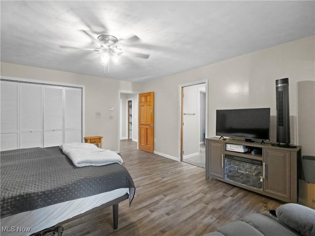 bedroom with a closet, a ceiling fan, baseboards, and wood finished floors