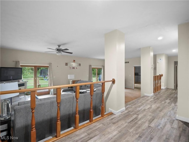 hall with wood finished floors, plenty of natural light, and an upstairs landing