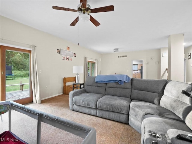 living area with a wealth of natural light, visible vents, carpet floors, and baseboards