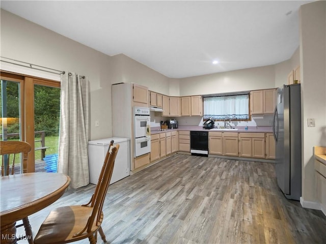 kitchen with under cabinet range hood, light brown cabinetry, dishwasher, freestanding refrigerator, and fridge