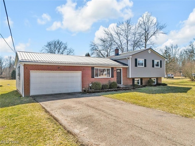 split level home featuring driveway, a front lawn, an attached garage, brick siding, and a chimney