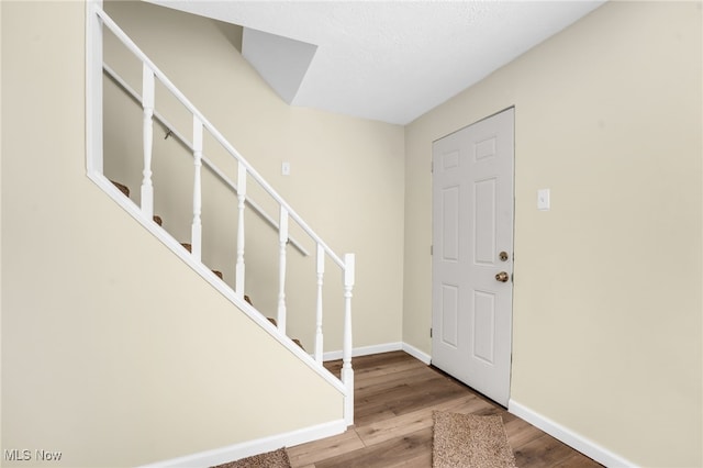 entryway with stairs, baseboards, and wood finished floors