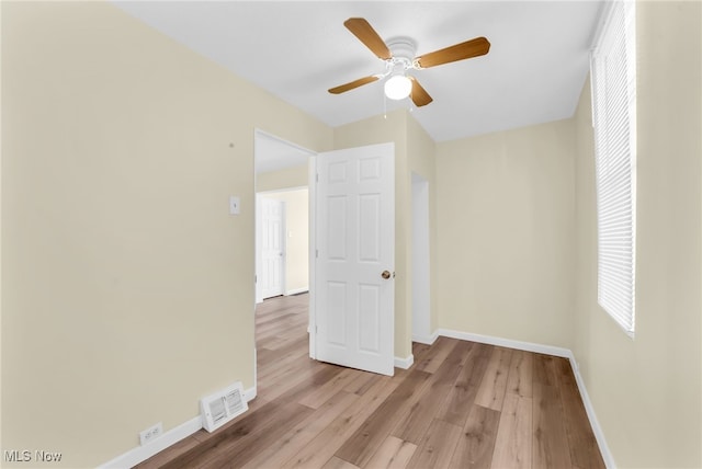 unfurnished room featuring visible vents, a ceiling fan, light wood-type flooring, and baseboards