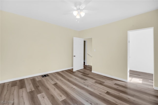 empty room with ceiling fan, visible vents, baseboards, and wood finished floors