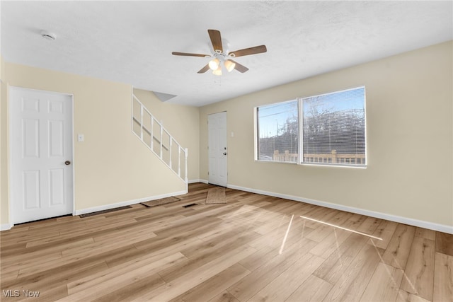 unfurnished living room with stairs, baseboards, and wood finished floors