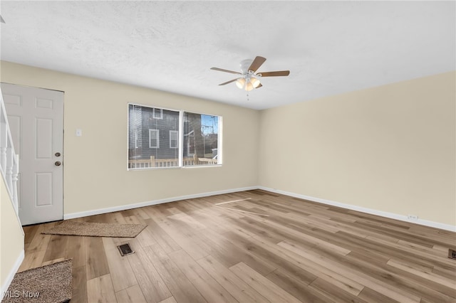 interior space with visible vents, a ceiling fan, a textured ceiling, wood finished floors, and baseboards