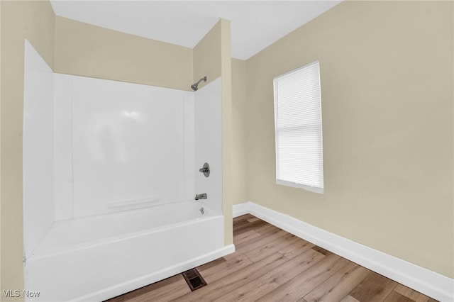 bathroom with bathing tub / shower combination, wood finished floors, and baseboards