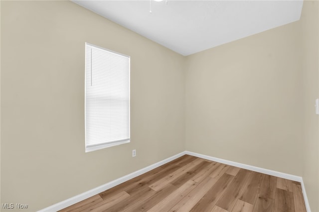 spare room with baseboards and light wood-style floors