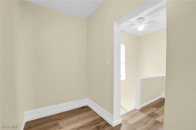 spare room with baseboards, wood finished floors, and a ceiling fan