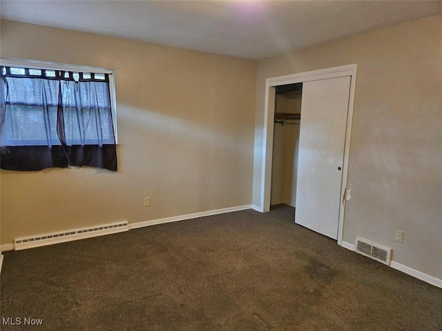 unfurnished bedroom with baseboard heating, baseboards, visible vents, and dark colored carpet