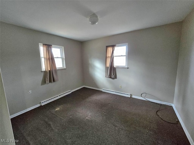 spare room featuring a baseboard radiator, baseboards, and a healthy amount of sunlight