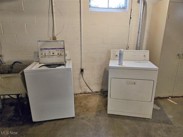 clothes washing area with laundry area, concrete block wall, separate washer and dryer, and a sink