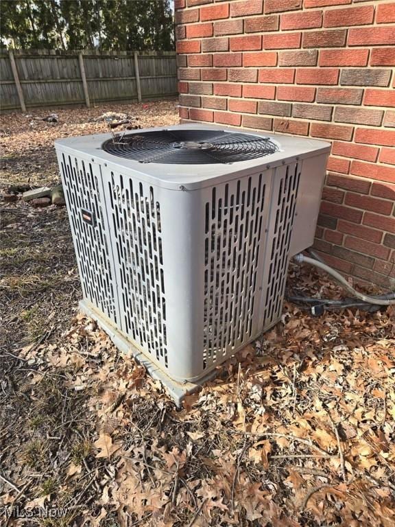 exterior details featuring cooling unit, brick siding, and fence