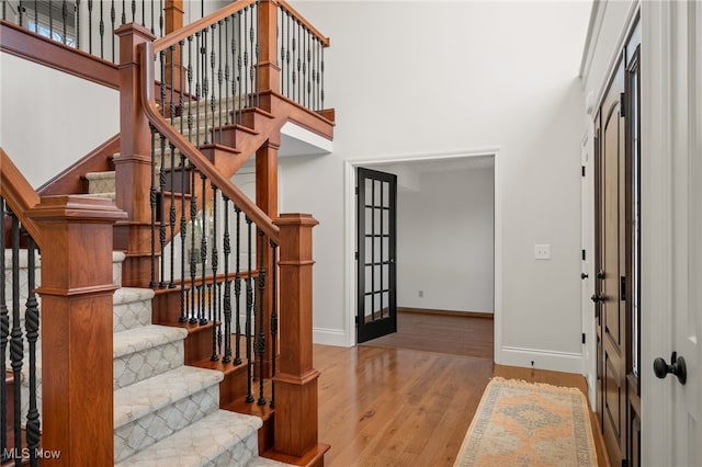 entryway with baseboards, a high ceiling, and wood finished floors