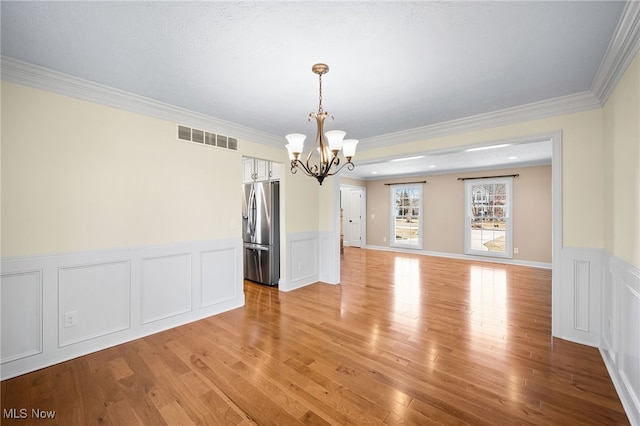 interior space with light wood-type flooring, visible vents, a notable chandelier, and crown molding