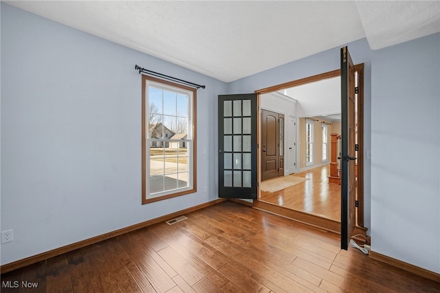 spare room featuring visible vents, baseboards, a textured ceiling, and hardwood / wood-style floors