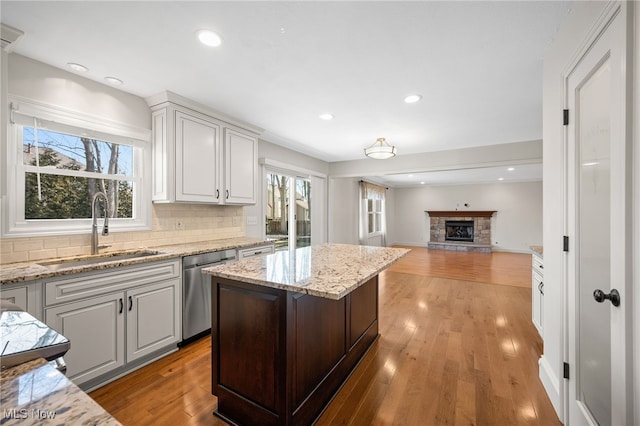 kitchen featuring dishwasher, decorative backsplash, light wood-style floors, and a sink