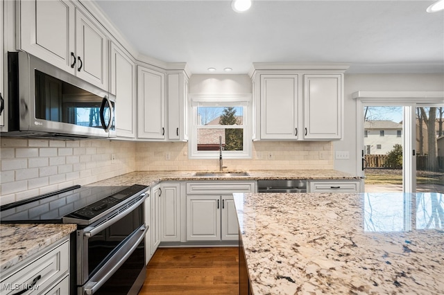 kitchen featuring dark wood finished floors, light stone counters, appliances with stainless steel finishes, white cabinets, and a sink