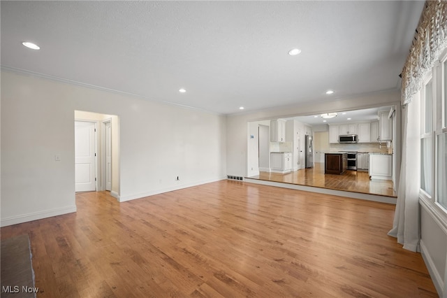 unfurnished living room featuring a sink, recessed lighting, light wood-style floors, crown molding, and baseboards