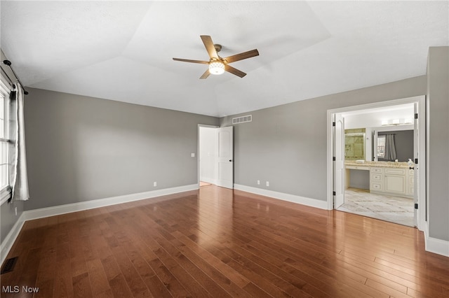 unfurnished bedroom with lofted ceiling, hardwood / wood-style flooring, baseboards, and visible vents