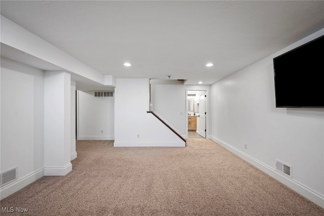 finished below grade area featuring recessed lighting, visible vents, and light carpet