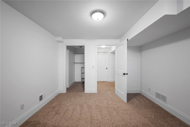 unfurnished bedroom with visible vents, baseboards, light colored carpet, and a spacious closet