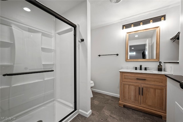 bathroom featuring vanity, a shower stall, toilet, and baseboards