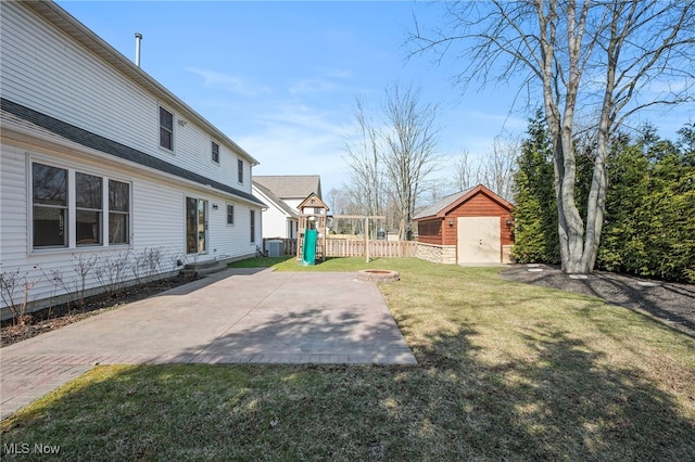 view of yard featuring an outbuilding, fence, a storage shed, a playground, and a patio area