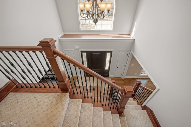 foyer featuring stairs, a notable chandelier, wood finished floors, and baseboards