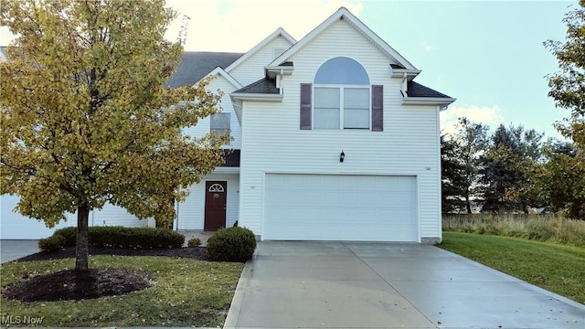 traditional home featuring concrete driveway, an attached garage, and a front yard