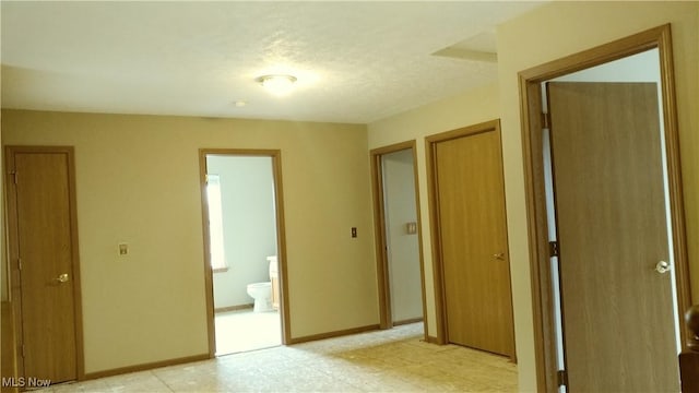 unfurnished bedroom featuring baseboards and ensuite bathroom