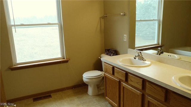 bathroom with a sink, visible vents, toilet, and double vanity