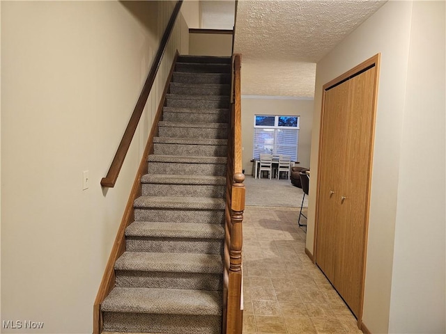 staircase with a textured ceiling