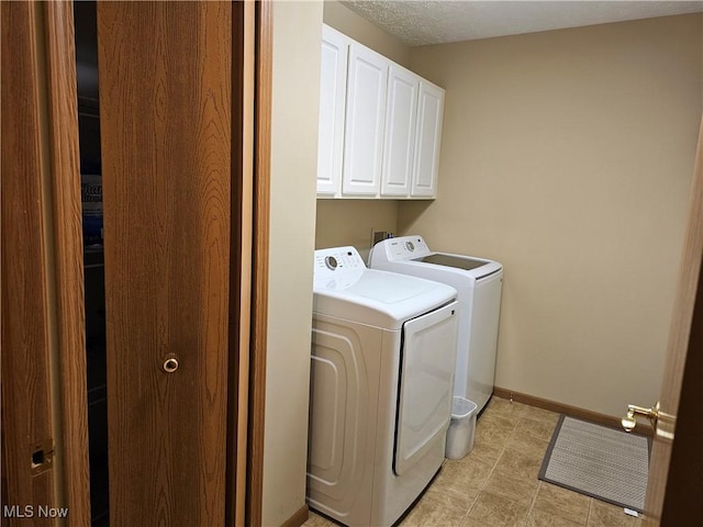 clothes washing area with baseboards, cabinet space, and washer and clothes dryer