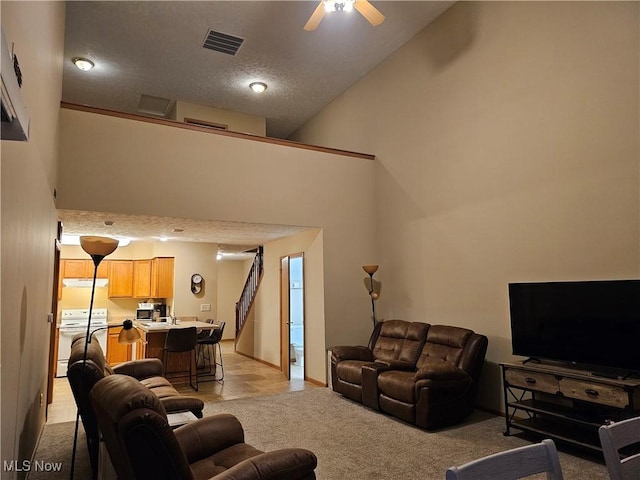 living room with visible vents, ceiling fan, light colored carpet, a high ceiling, and a textured ceiling