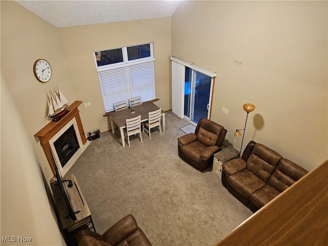 living room with carpet floors, high vaulted ceiling, and a fireplace