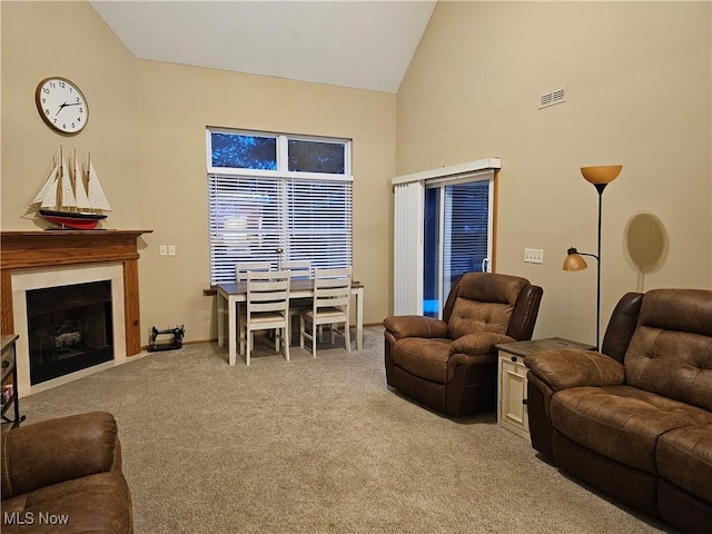 living area with a premium fireplace, visible vents, high vaulted ceiling, and carpet floors